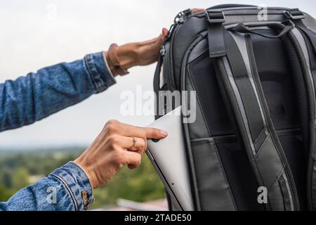 Woman packing a laptop in backpack for a trip Stock Photo