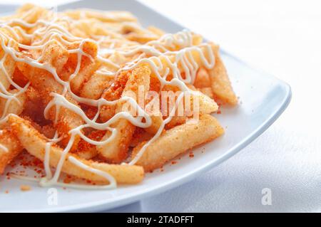 French fries decorated with mayonnaise and balado seasoning are placed on a white plate Stock Photo