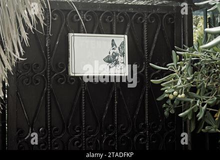 Faded 'Beware of the Dog' (in Italian) sign on garden fence gate Stock Photo