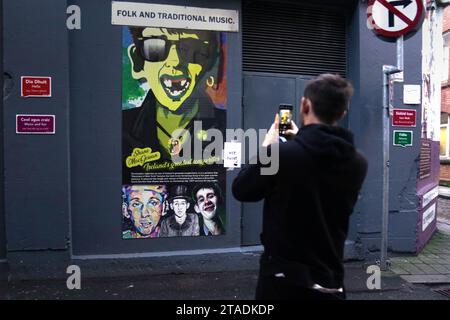 A man photographs an image of Shane MacGowan, lead singer of The Pogues, on a building in the Temple area of Dublin. Shane MacGowan has died aged 65, his wife has announced in a post on Instagram. Picture date: Thursday November 30, 2023. Stock Photo