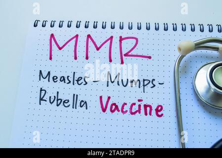 Concept of MMR - Measles Mumps Rubella Vaccine write on book with stethoscope isolated on white background. Stock Photo