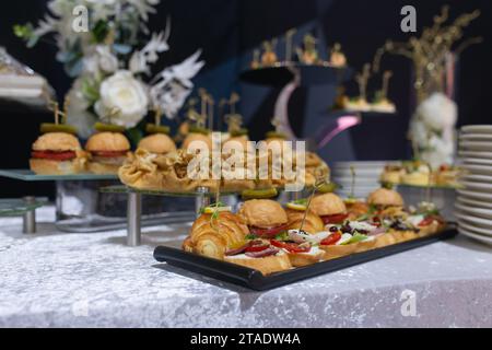 Croissants, burgers and various snacks on stands on the buffet table. Stock Photo