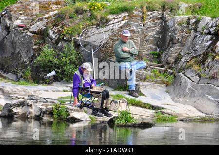 Old men resting and fishing on a bright summers day besides the river Teifi at Cenarth near Castle Emlyn in Wales. Stock Photo