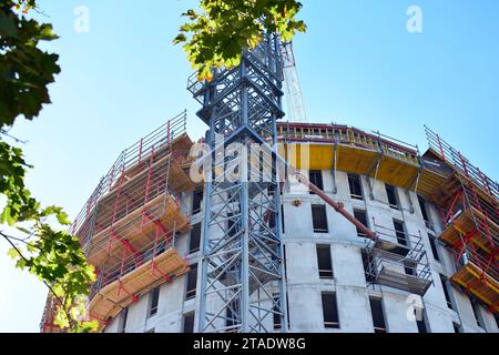 High rise building under construction. Installation of glass facade panels on a reinforced concrete structure. Stock Photo