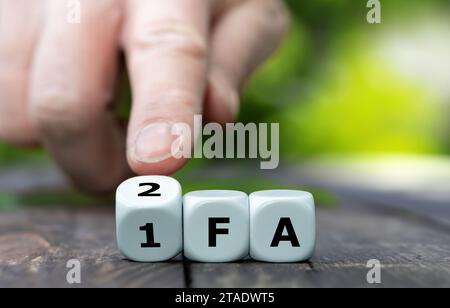 Hand turns dice and changes the abbreviation 1FA (One factor authentication) to 2FA (Two factor authentication). Stock Photo