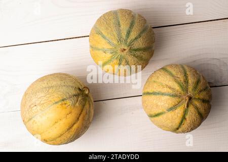 Three Melons Three fragrant juicy, organic melons, with a bamboo tray, close-up, on ...