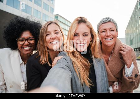 Group of real successful business woman smiling and having fun taking a selfie portrait together. Teamwork of entrepreneur females looking at camera. Happy startup executive ladies laughing at work. High quality photo Stock Photo