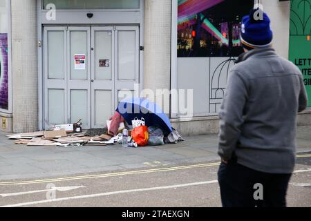 London, UK. 30th Nov, 2023. A man looks at the belongings of a homeless person who sleeps on the pavement in central London. Emergency accommodation will be set for London's rough sleepers as the Mayor of London has implemented severe weather protocol in London amid freezing weather in the coming days. Credit: SOPA Images Limited/Alamy Live News Stock Photo