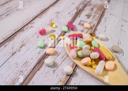 Mixed medicine pills, tablets on wooden spoon on blue background. Many different pills with space for text. Health care. Top view. Copy space. New ima Stock Photo