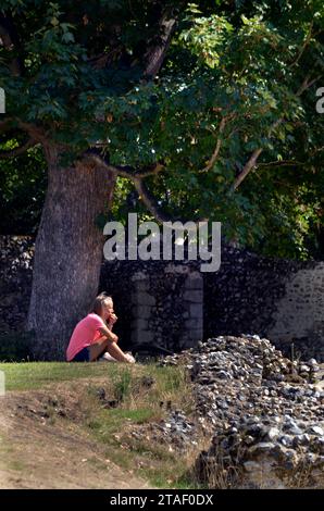 lone women  sitting in sun eating apple bury st edmunds suffolk england Stock Photo