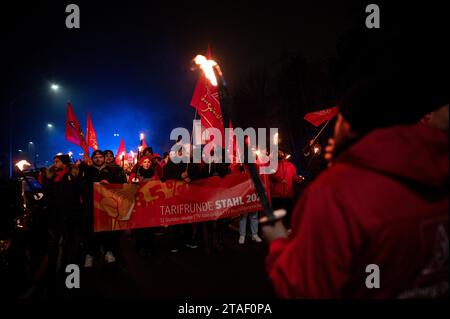 Duisburg, Germany. 30th Nov, 2023. Participants in the demonstration walk to the viewing platform during a protest in the course of the current wage dispute. Trade unionists from the Duisburg steelworks and delegations from surrounding branches symbolically herald the end of the peace obligation. The trade unionists make a torchlight march from the Hüttenschenke of Hüttenwerke Krupp Mannesmann to the viewing platform at Tiger & Turtle in Duisburg. Credit: Fabian Strauch/dpa/Alamy Live News Stock Photo