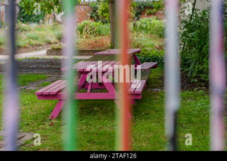 Multicolored garden chair and table seen through iron bars. Stock Photo