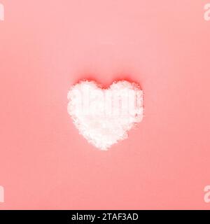 Heart made of snow on pink background. Valentines day concept. Top view, flat lay. Stock Photo