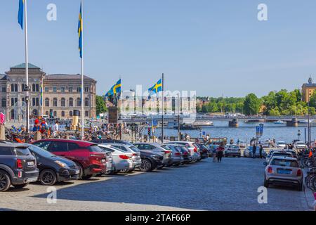 View of outdoor parking place near the Royal Palace on waterfront in central Stockholm. Square is adorned with national flags in honor of Sweden's Stock Photo