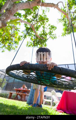 Boy on a round rope swing in the backyard, Miami, Florida, USA Stock Photo
