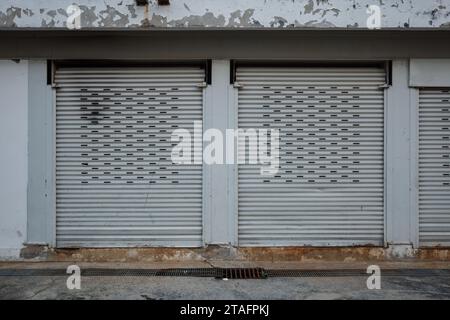 Outdoor exterior front view, Secured Storefront, Weathered Roller Shutter Doors on old Building Stock Photo