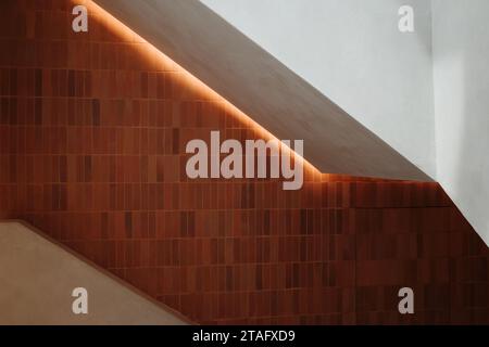 Modern white Staircase and railing surrounded by brick wall with Light and Shadow. Stock Photo