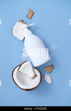 White cosmetic bottle of shampoo, soap or shower gel with a dispenser on the blue background of a broken coconut. Mockup for cosmetic ads. Viewed from Stock Photo