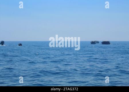 Blue whale's backs emerging from the water and small fishing ships on the background on a sunny day during whale watching tour, Mirissa, Sri Lanka Stock Photo