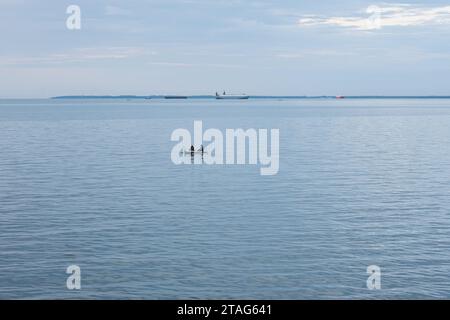 Two fishermen begin their day by going out to sea in search of fish on a cloudy morning. Stock Photo