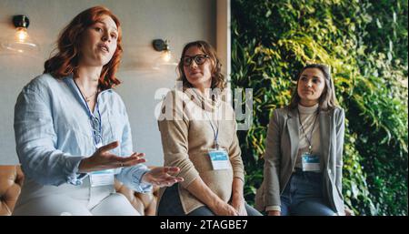 Female professionals engage in a business meeting, discussing work-related topics. The office setting showcases teamwork and collaboration among colle Stock Photo