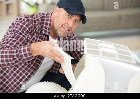 male technician installing outdoor air conditioning unit Stock Photo