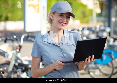 woman bike mechanic using pc to fix bikes outdoors Stock Photo
