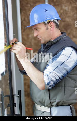male builder is measuring a window Stock Photo