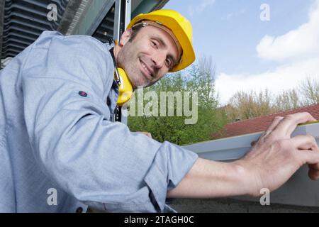 man worker in helmet installing metal sill on window frame Stock Photo