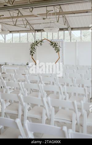 A set of white ceremony chairs arranged in neat rows for a wedding, ready to be filled with guests Stock Photo