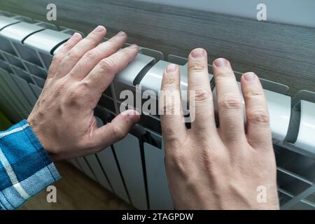 male touching barely warm battery during heating season. Heating devices in the house, side view. discomfort from the cold Stock Photo