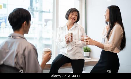 Group of friendly and happy, diverse Asian businesspeople are enjoying chatting during a coffee break in the break room together. teamwork, colleagues Stock Photo