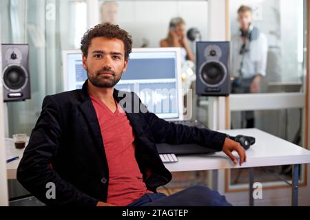 Portrait, media and a man producer in a recording studio mixing audio with a sound desk. Computer, tech or music with a serious young DJ or engineer Stock Photo