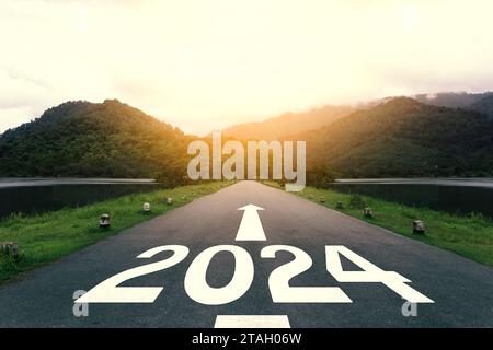 The new year 2024 or straightforward concept. Text 2024 written on the asphalt road at sunset. Stock Photo