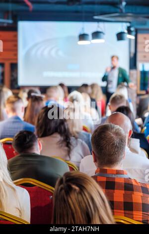 Back view of multiethnic business professionals listening to speaker giving presentation in conference hall Stock Photo
