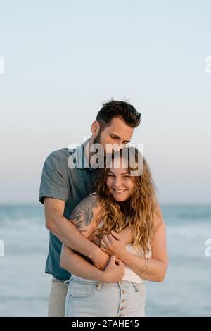 Man Kissing his Wife on top of the head at the beach Stock Photo