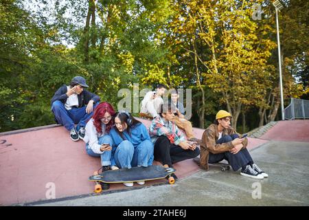 group of young people looking at phones in a skate park Stock Photo