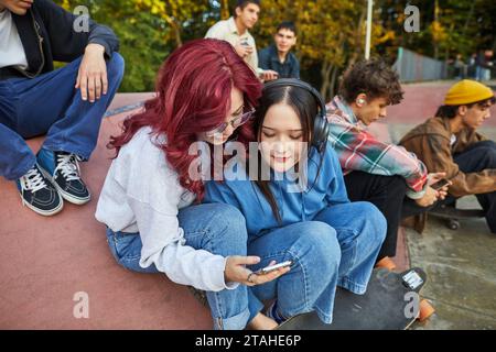 two girls looking at  phone in  skate park Stock Photo