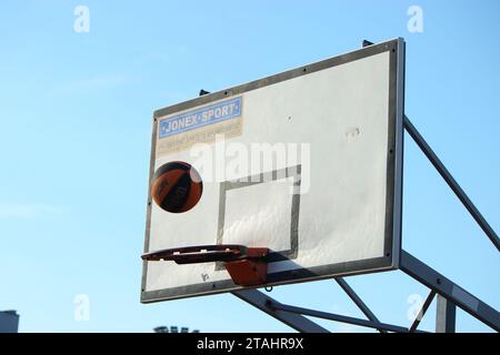 A basketball falling into a hoop against a blue background in Namyslow, Poland Stock Photo