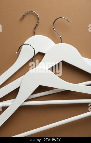 White hangers on brown background, top view Stock Photo