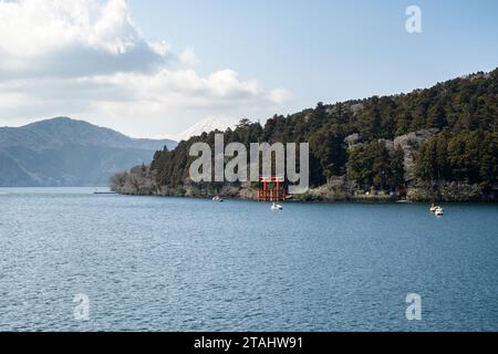 Mount Fuji just visible in the distance behind the Torii Gate for Hakone Shrine on the shore of Lake Ashinoko, Hakone, Japan. Taken from on board the Stock Photo