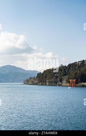 Mount Fuji just visible in the distance behind the Torii Gate for Hakone Shrine on the shore of Lake Ashinoko, Hakone, Japan. Taken from on board the Stock Photo