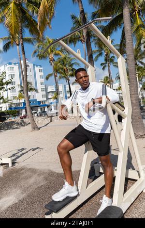 full length of african american sportsman working out on outdoor gym equipment in Miami beach Stock Photo