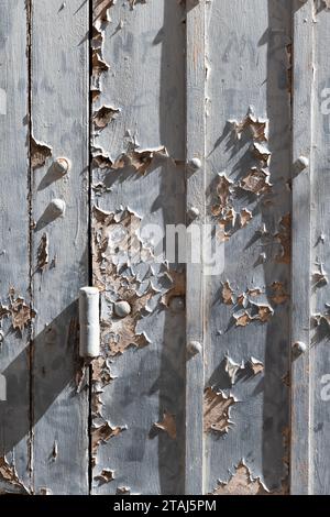 Detail of a section of an Italian building with wood boards with peeling, aged, white paint, cracks and damages. Stock Photo
