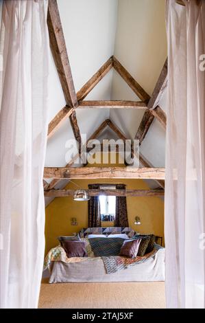 Sofa under spacious beamed attic ceiling in Georgian barn conversion, Tetbury, Gloucestershire, UK. Stock Photo