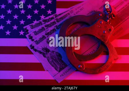 US Tax refund check and handcuffs on flag of United States of America close up. Record criminal investigation Stock Photo