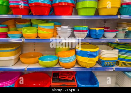 Multicolored plastic bowls, baskets and colanders on shelves for sale Stock Photo