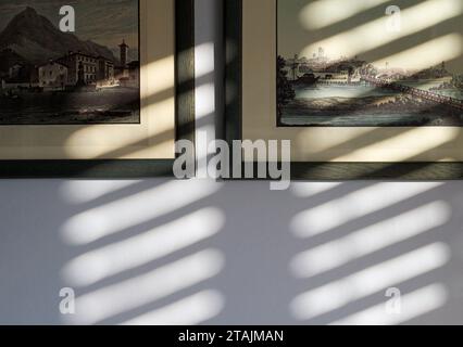 shadows and sunlight through window blinds on antique prints Stock Photo