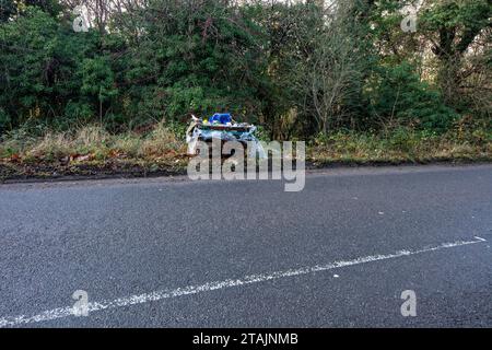 Environmental pollution in the form of a very large, commercial sized, bag of waste fly-tipped beside a busy road in the countryside Stock Photo