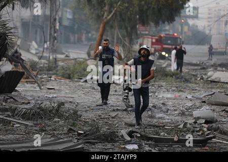 Journalists, who have risked their lives to cover the bombings in Gaza, walk through an area destroyed by Israel air strikes. Gaza City. Palestine. Stock Photo